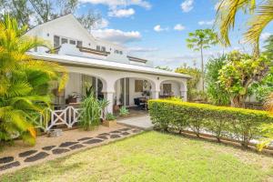 a white house with a garden and palm trees at Villa Marea - Exceptional Beachfront Sanctuary in Tamarin