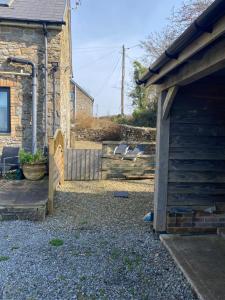 a yard with a stone house and a fence at The Threshing Barn Loft in Pont-y-Berem