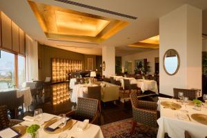 a restaurant with white tables and chairs and a mirror at The Oberoi Mumbai in Mumbai