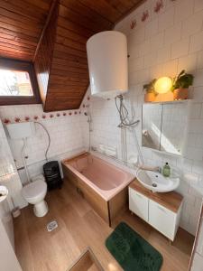 a bathroom with a pink bath tub and a sink at Keltafok Apartman, Balatonföldvár in Balatonföldvár