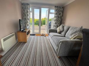 a living room with a couch and a tv at Greenbanks 2 Damerham Self Catering in Damerham