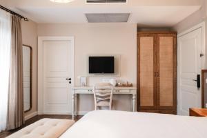 a bedroom with a bed and a desk with a television at Viento Alacati Hotel in Alaçatı