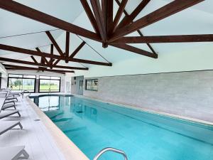 a large swimming pool with wooden ceilings and chairs in a building at Holiday Inn Calais Coquelles by IHG in Coquelles