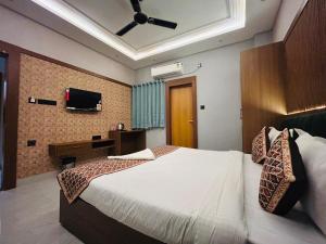 a bedroom with a large bed with a ceiling fan at Sanidhyam by Hotel Sahu near Temple in Varanasi