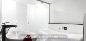 a white bathroom with a sink and a tub at 렉시호텔 in Seoul