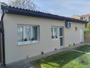 a white house with two windows with flower pots at Cyclo Apartment Pinki in Bačka Palanka