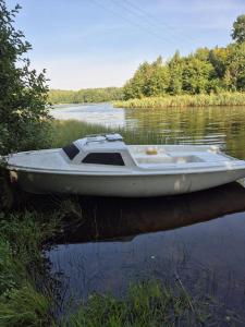 a white boat is sitting on the water at Domek na Kaszubach w Potęgowie in Kamienicki Młyn +7 photos