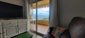 a living room with a television and a balcony at Calpe vistas al mar in Ifach