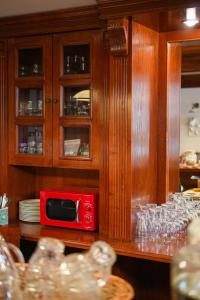 a red microwave in a wooden cabinet with glasses at Art'e Boutique Rooms in Băile Tuşnad +87 photos