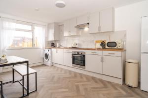 a kitchen with white cabinets and a wooden floor at Willow retreat in Royal Tunbridge Wells