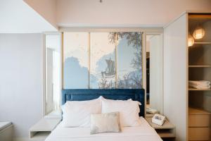 a bedroom with a bed with a blue headboard at Lavy at Anderson Pakuwon Mall in Surabaya