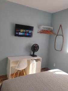 a bedroom with a bed and a desk and a tv at Haurea House in São Luís