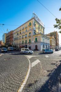 a large yellow building with cars parked in a street at Angioino Central in Naples