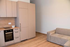 a kitchen with white cabinets and a couch in a room at Prie jūros in Melnragė