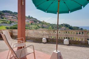 a patio with a chair and an umbrella on a balcony at Villa Flora - Goelba in Capoliveri