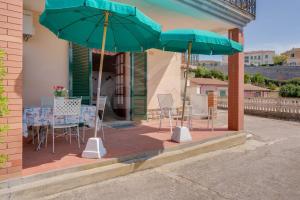 a patio with a table and chairs and umbrellas at Villa Flora - Goelba in Capoliveri