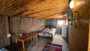 a room with a bed and a table and a refrigerator at Zman Midbar Eco Spirit Lodge for Peace in Arad +94 photos