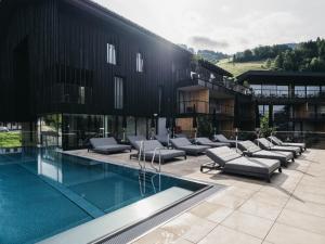 a building with a pool with lounge chairs next to it at Haven Mountain Retreat in Sankt Johann im Pongau