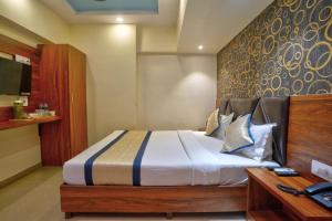 a bedroom with a large bed with a wooden headboard at Hotel Saineel Residency in Mumbai