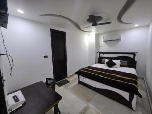 a bedroom with a bed and a table and a ceiling fan at The Redcarmine in New Delhi