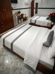two beds in a hotel room with white sheets at CT Morning Hotel in Can Tho