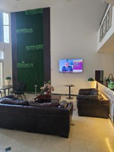 a living room with two couches and a flat screen tv at Hotel Izzy Stay in Maputo