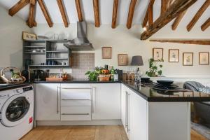 a kitchen with white cabinets and a washer and dryer at Blackham Farm in Hartfield