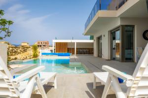 a house with a swimming pool and two lawn chairs at Villa Sophia in Busot