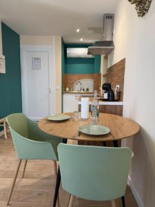 a kitchen with a wooden table and green chairs at La Jungle - A71 - Jacuzzi et Cinéma in La Chapelle-Saint-Ursin