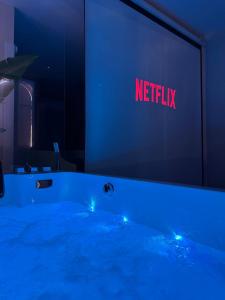 a swimming pool with a netflix sign on a wall at La Jungle - A71 - Jacuzzi et Cinéma in La Chapelle-Saint-Ursin