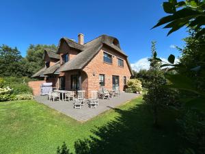 a large brick house with tables and chairs in front of it at Reetdachhaus Nordstern in Garding