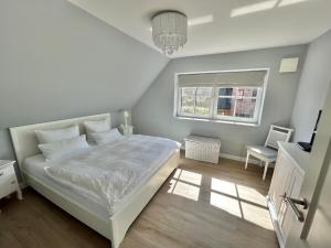 a bedroom with a white bed and a window at Reetdachhaus Nordstern in Garding