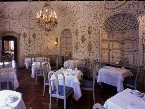 un restaurante con mesas y sillas blancas y una lámpara de araña en Sina Villa Matilde, en Romano Canavese