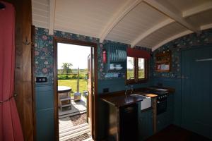a kitchen with blue walls and an open door at Charlotte-Rose Shepherd's Hut in Hethersett