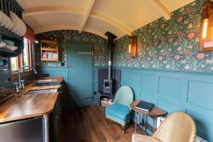 a kitchen with blue walls and floral wallpaper at Charlotte-Rose Shepherd's Hut in Hethersett +21 photos