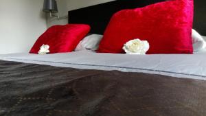 a bed with red pillows and white flowers on it at Carpe Diem in Ommen