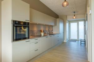 a kitchen with white cabinets and a large window at Aalborg Hotel Apartments in Aalborg