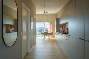 a kitchen with white cabinets and a table with a mirror at Aalborg Hotel Apartments in Aalborg