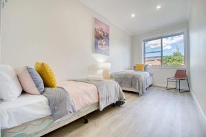 a room with two beds and a couch and a window at Coastal & Connected Summer Resort Parking in Cronulla