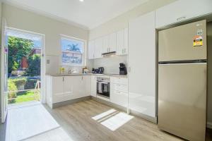 a kitchen with white cabinets and a stainless steel refrigerator at Coastal & Connected Summer Resort Parking in Cronulla
