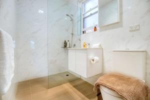 a white bathroom with a shower and a sink at Coastal & Connected Summer Resort Parking in Cronulla