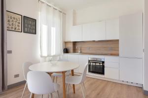 a white kitchen with a white table and chairs at Lexia Suite in Lesa +11 photos
