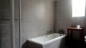 a bathroom with a bath tub and a shower at FRANCHISE BENONI GUEST HOUSE in Benoni +32 photos