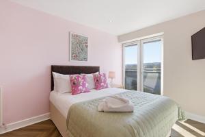 a white bedroom with a bed with pink pillows and a window at High Quays Apartments - Properties Unique in Newcastle upon Tyne