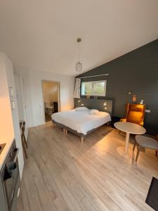 a bedroom with a bed and a table in it at Hôtel Les Voisins Beaucemaine in Ploufragan