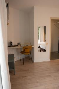 a room with a table and a yellow chair at Hôtel Les Voisins Beaucemaine in Ploufragan