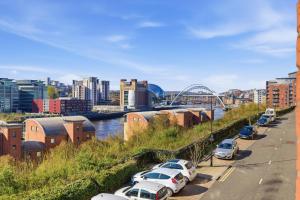 a row of cars parked in a parking lot next to a river at High Quays Apartments - Properties Unique in Newcastle upon Tyne