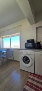 a kitchen with a washing machine and a table with chairs at Casa Mar in Costa da Caparica