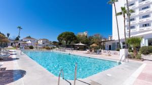 a swimming pool with chairs and a building at BLUESEA Costa Serena in Torremolinos