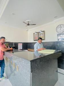 two men standing at a counter in a kitchen at Hotel Har Ki Pauri with terrace Ganga view in Haridwār